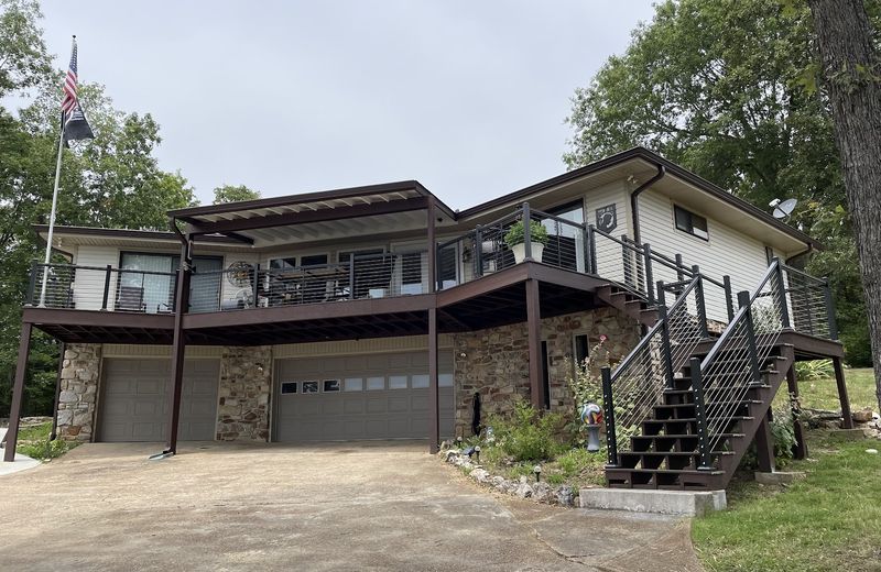 A finished home with a long upper deck and stone base