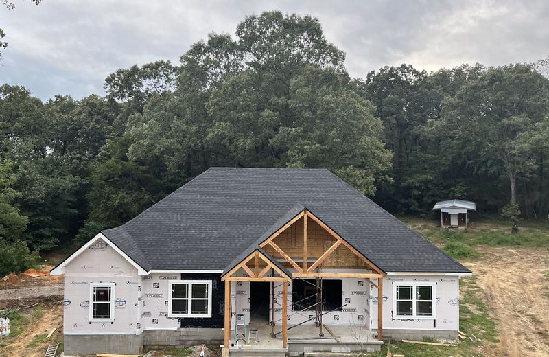 A house with its roof and timber porch framing complete, ready for siding