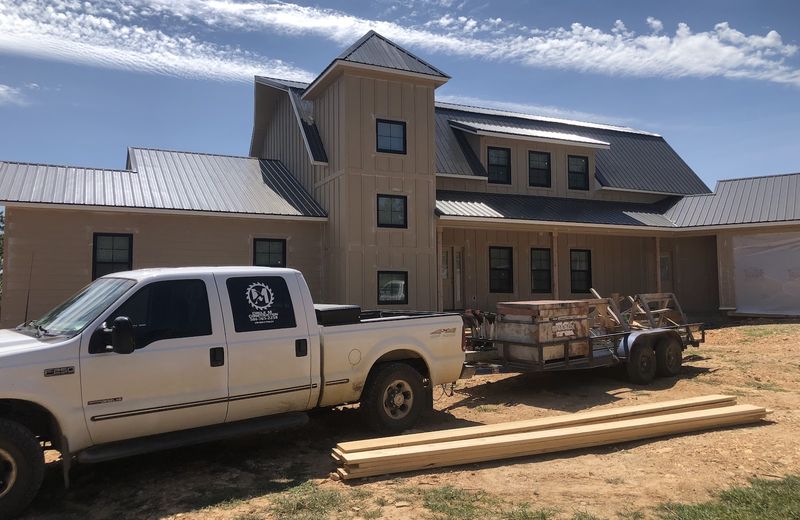 A multi-story home in cedar and metal siding nearing completion