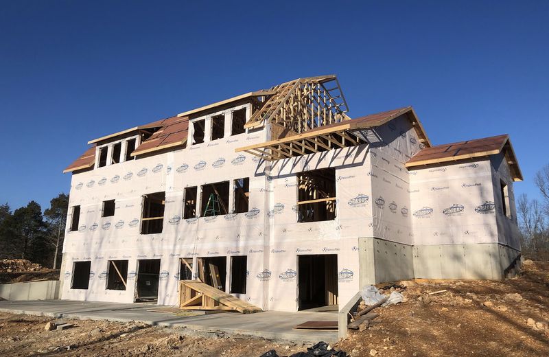 A three-story house under construction with the roof going on