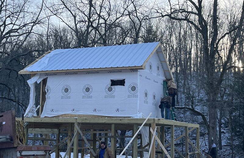 A tall narrow build with a standing-seam roof on pier framing