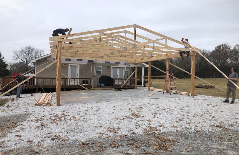 Post-frame roof framing going up over a house addition