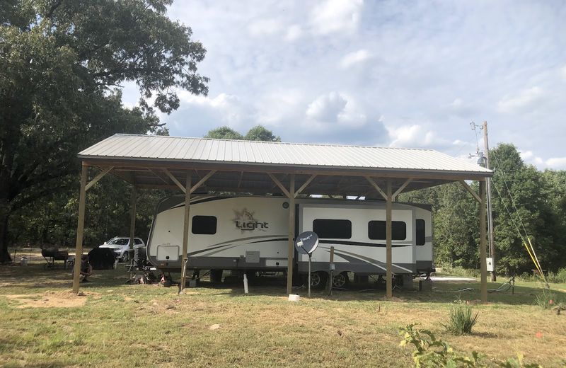 A tall open carport sheltering a travel trailer